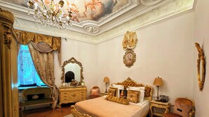 A classic bedroom with a large bed, ornate dresser, and a chandelier. - Conacul Coroanei Luxury Boutique (Bucharest)