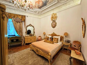 Un dormitorio clásico con una cama grande, un aparador decorado y una araña.