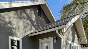 A residential building with a front entrance, a small porch, and a set of concrete steps leading up to the door.