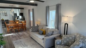 A modern living room with a sofa, armchair, dining table, and chairs.