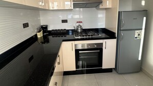 Une cuisine moderne avec des armoires blanches, un plan de travail noir, une cuisinière en acier inoxydable et un four encastré.