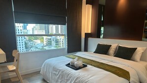 Een hotelkamer met een groot bed, uitzicht op de stad, een stoel en een bureau.