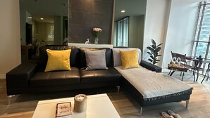 Een moderne woonkamer met een modulaire bank, een witte salontafel en een eethoek met een tafel en stoelen.