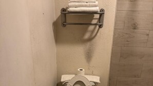 Un baño pequeño con inodoro, una estantería con toallas y una bañera.