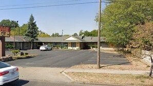 Un motel vacacional con estacionamiento, un edificio de una planta y un cartel.