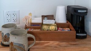 En træbakke med kaffekopper, en kaffemaskine og forskellige ting på et træbord.