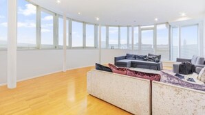 A spacious living area with large windows, a wooden floor, and a modern sofa set.