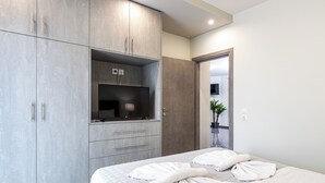 A modern bedroom with a large bed, grey wardrobe, and a television. - Mariam Luxury Apts B2 (Chania)