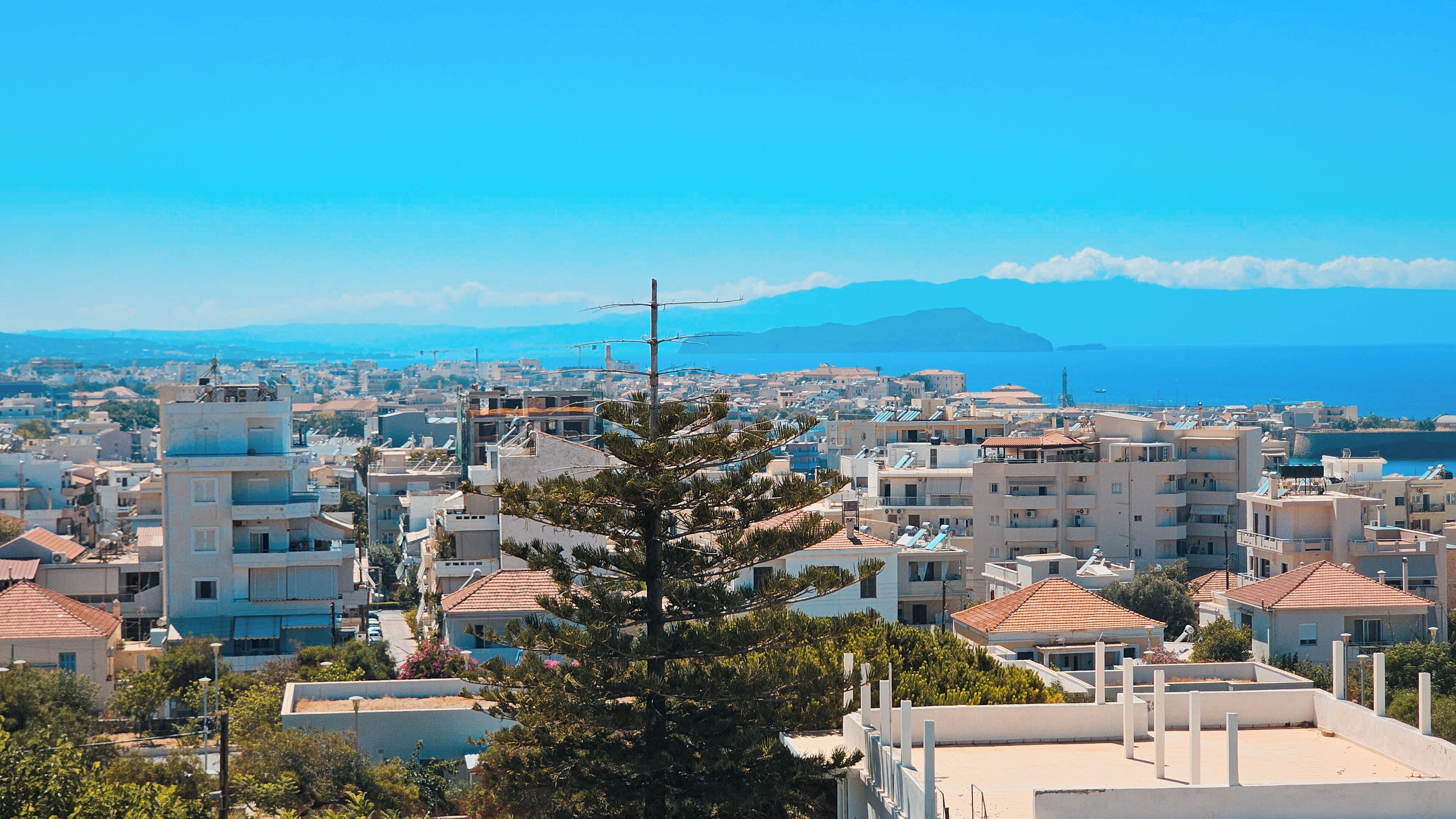 A coastal cityscape with a mix of residential buildings and a prominent mountain in the background.