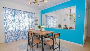 Ein Essbereich mit einem Holztisch und Stühlen, einer blauen Wand und einem großen Spiegel, der den Raum reflektiert.