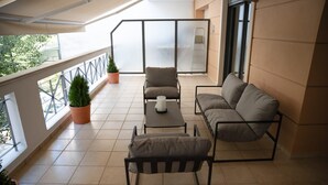 A balcony with a sofa, armchair, and table, potted plants, and a view of the outside. - Wonderful central apartment with private parking space. (Larisa)