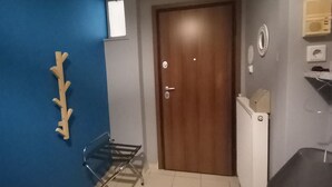 Un corridoio con una parete azzurra, una porta in legno, un termosifone e una piccola finestra.