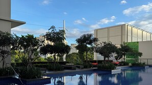 A swimming pool with clear blue water, surrounded by greenery and modern buildings.