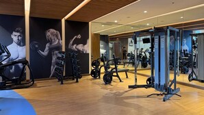 A modern gym with exercise equipment, wooden flooring, and a large mirror wall.