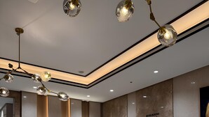 A spacious lobby with a polished floor, modern lighting fixtures, and a mailroom sign.