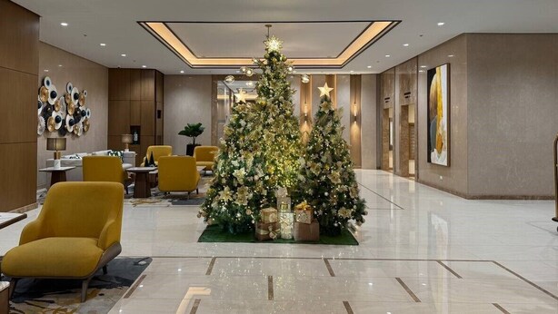 A spacious lobby with a large Christmas tree, modern furniture, and a chandelier.