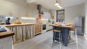 Et moderne køkken med en central ø, barstole og en indbygget ovn.