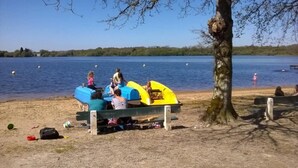 Un paesaggio con un lago, una panchina e canoe.
