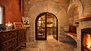 A stone-walled room with a fireplace, a wooden dresser, and a glass display case. - Fortaleza Medieval La Manyosa (Granera)