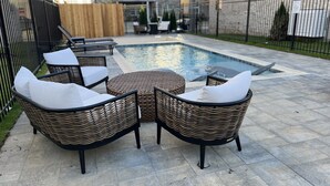 Zona de piscina con mobiliario de mimbre y una piscina pequeña.