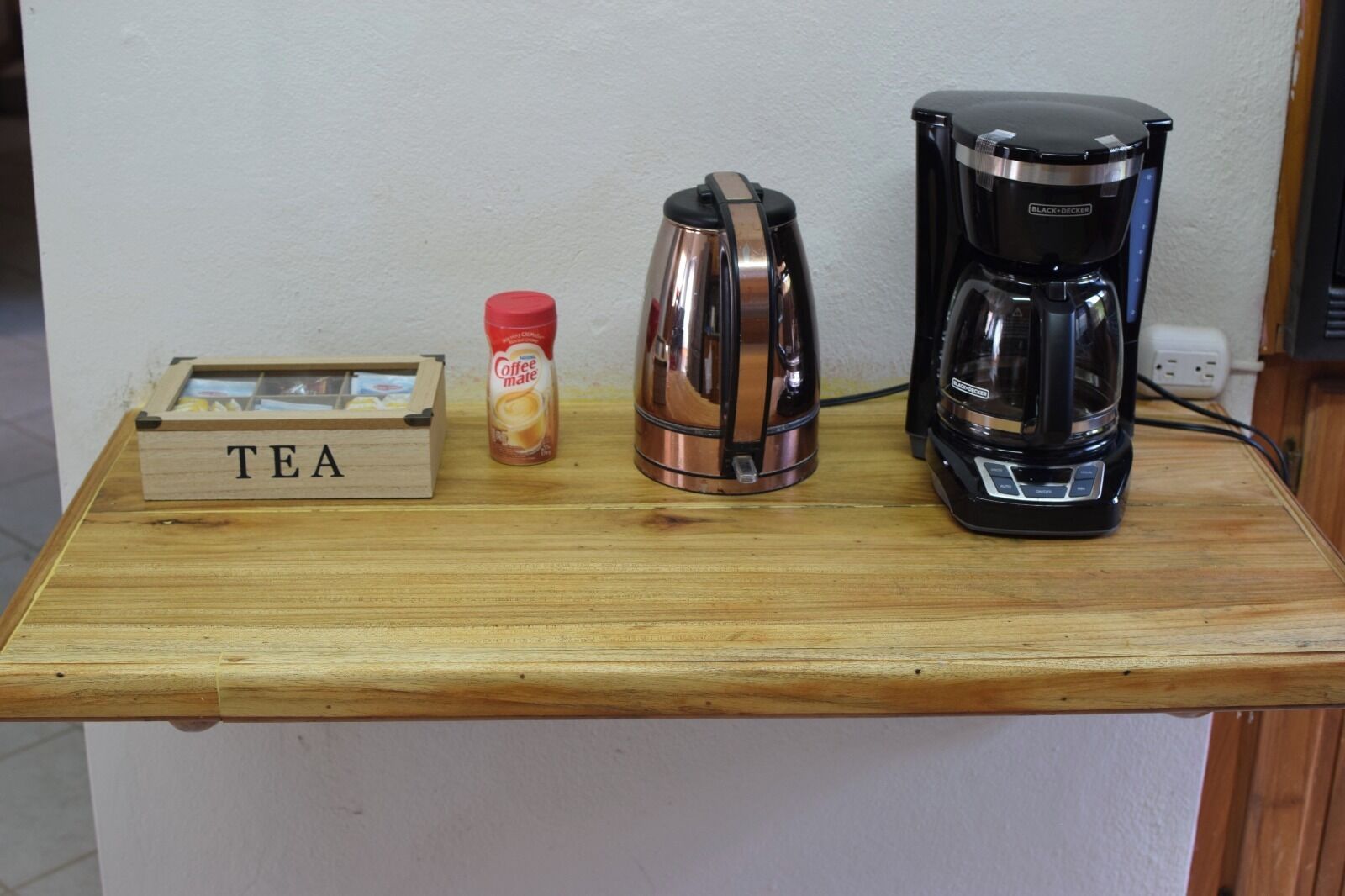 Une étagère en bois avec une boîte à thé, une machine à café et une bouteille de café.