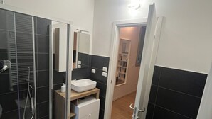 Un baño moderno con cabina de ducha de vidrio, un lavabo blanco y un espejo.