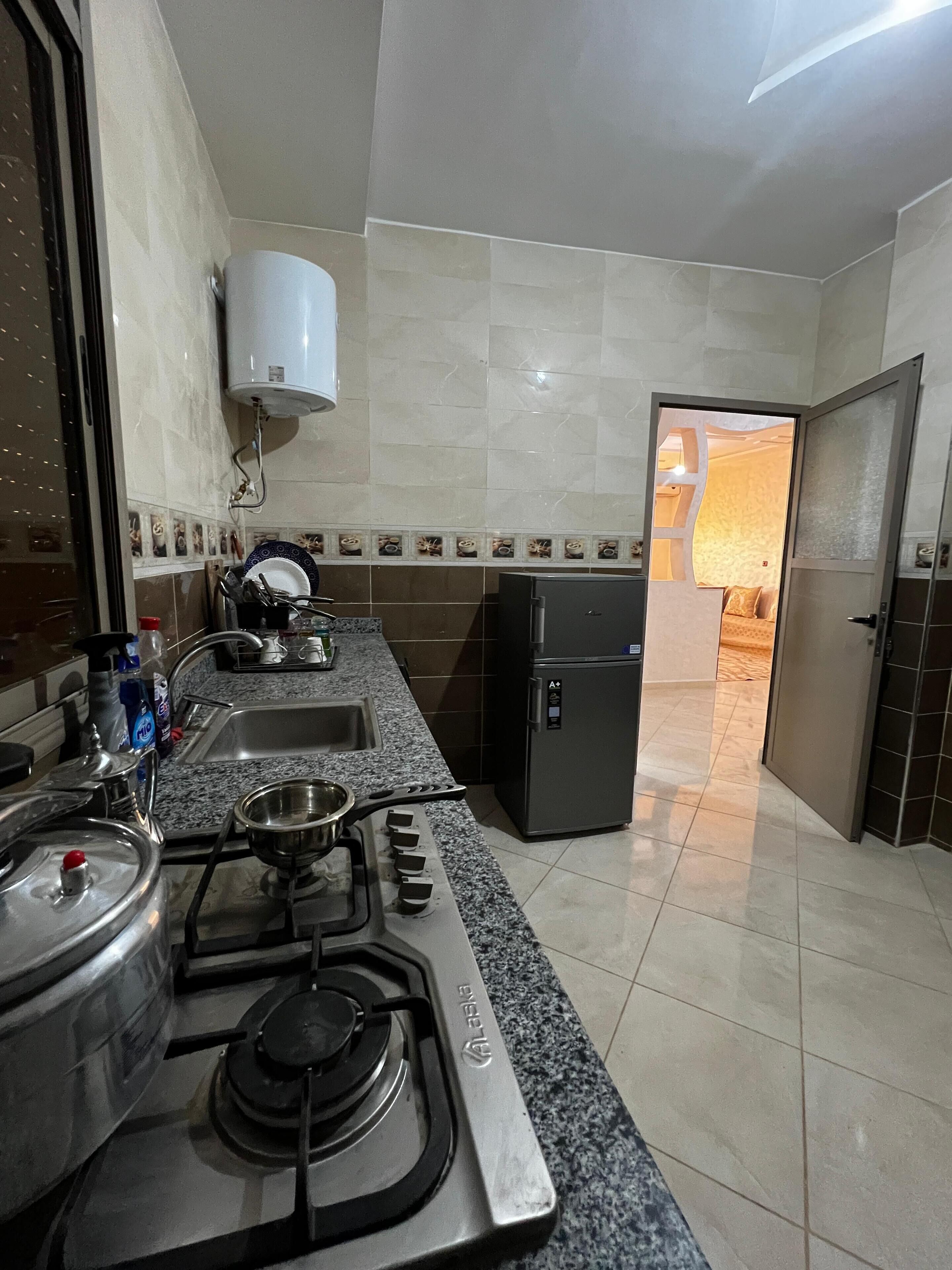 A kitchen with a gas stove, sink, and a refrigerator.