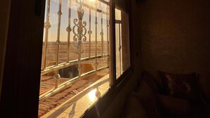 A room with a large window, a sofa, and a view of a barren landscape. - nomad apartments (Taouz)