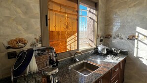 A modern kitchen with granite countertops, stainless steel appliances, and a window with a view of the outside. - nomad apartments (Taouz)