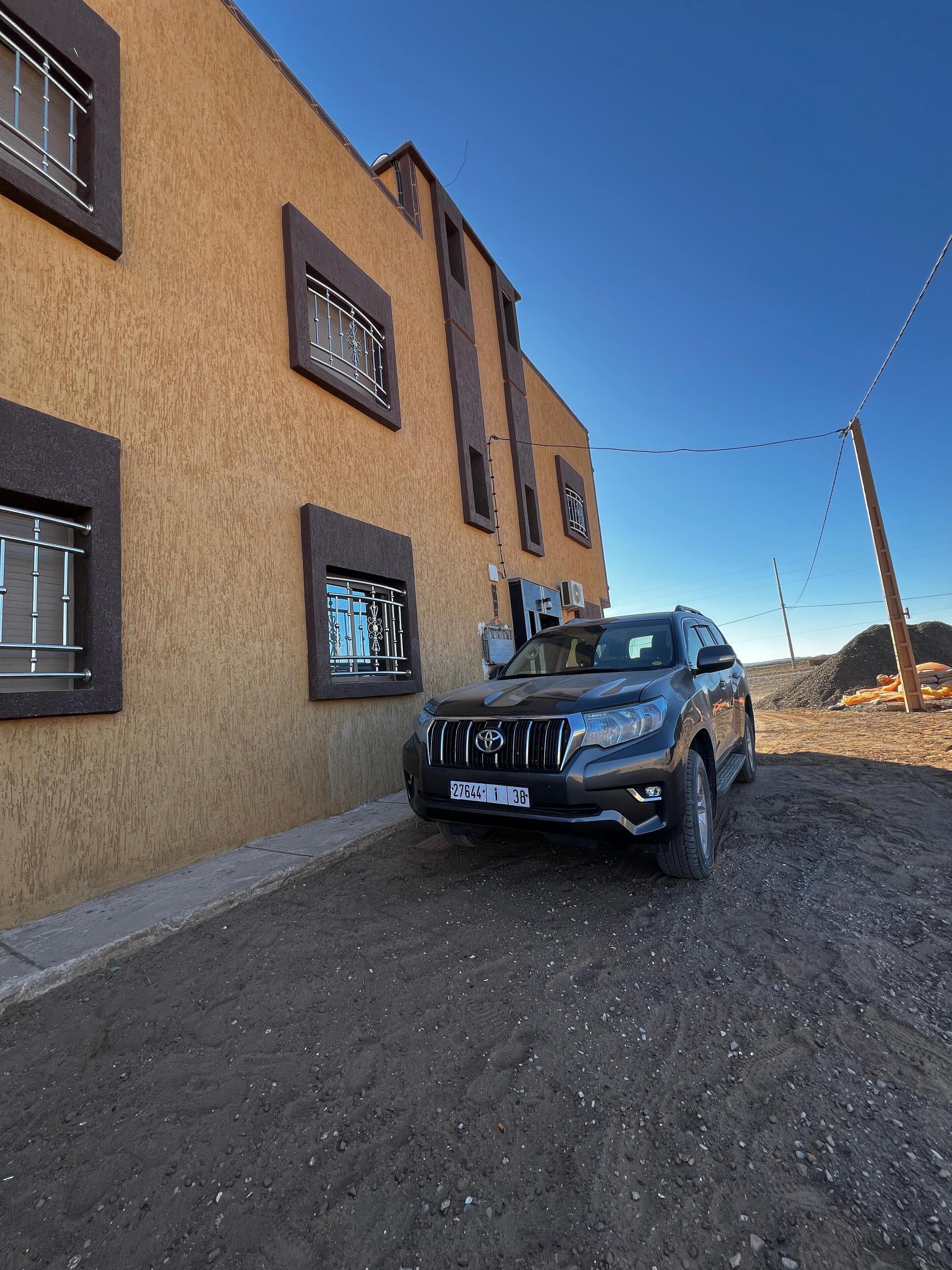 Un SUV nero parcheggiato davanti a un edificio con facciata color beige e infissi scuri.