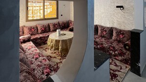 A modern interior with a sectional sofa, a round coffee table, and a view through an arched doorway. - nomad apartments (Taouz)