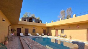 A pool area with tiled flooring, lounge chairs, and a clear blue sky. - nomad apartments (Taouz)