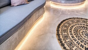 A modern, circular room with a sofa, a bed, and hanging lights. - 360o 2BD Panoramic Apartment (Santorini)