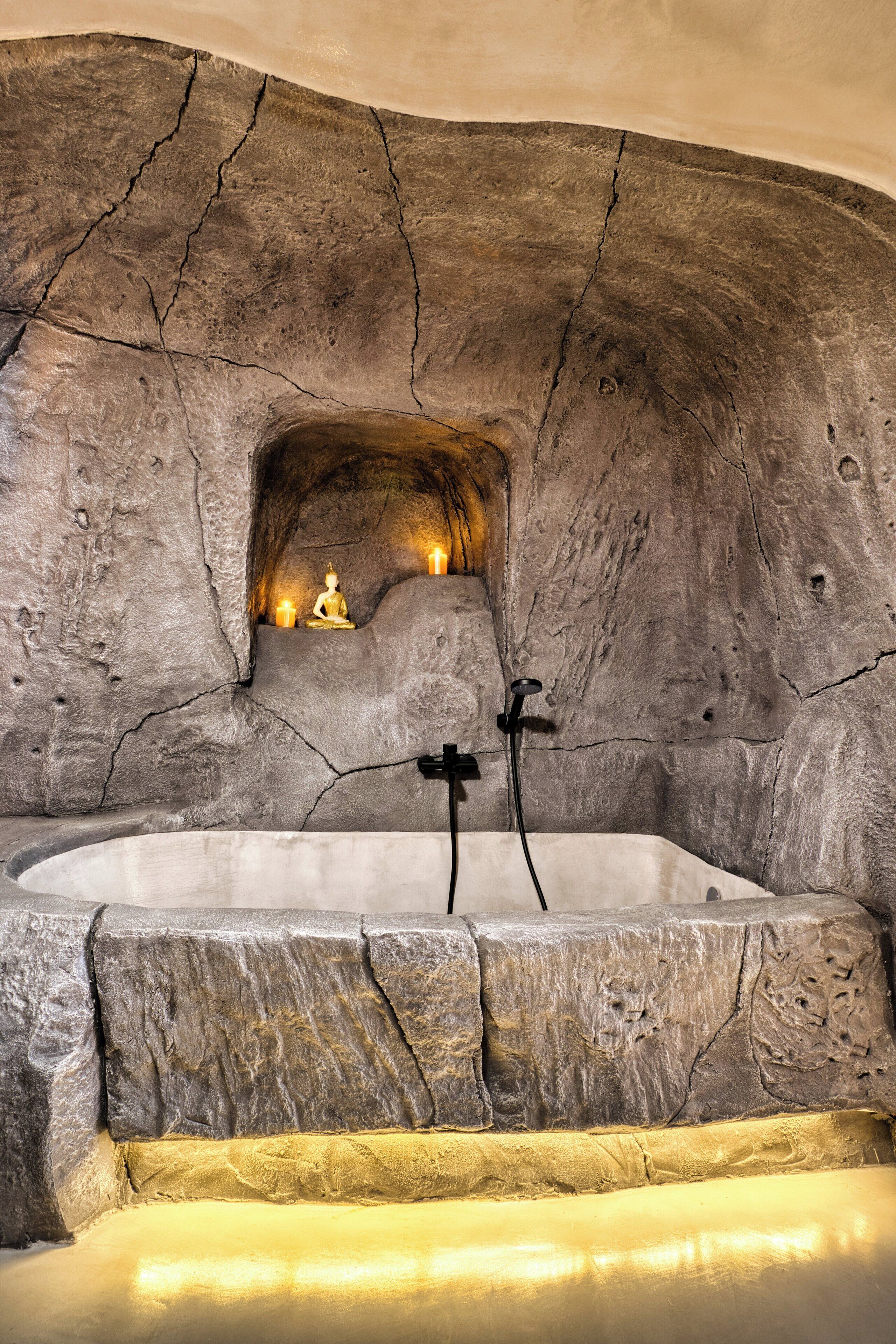 Una bañera de piedra con estante integrado, velas y una estatua de Buda.