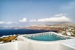 Ein Pool mit einer Fliesenbordsteinkante, mit Blick auf eine Küstenstadt und Klippen.