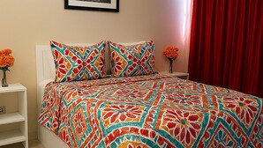 A bedroom with a bed, a nightstand, a vase with flowers, and a framed picture on the wall. - Affordable Queen Room w/ Patio | Near Baha Mar & Airport (Nassau)