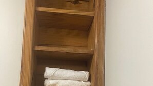 A wooden shelf unit with folded white towels and a bar of soap. - Affordable Queen Room w/ Patio | Near Baha Mar & Airport (Nassau)