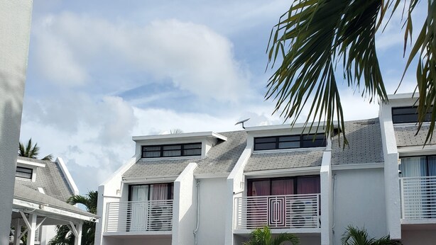 A modern hotel with a swimming pool, white exterior walls, and balconies with railings. - Affordable Queen Room w/ Patio | Near Baha Mar & Airport (Nassau)