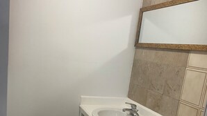 A small bathroom with a white sink, a toilet, and a mirror above the sink. - Affordable Queen Room w/ Patio | Near Baha Mar & Airport (Nassau)