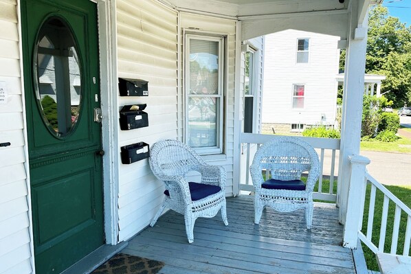 A porch with two wicker chairs, a green door, and mailboxes. - Centrally located off Back Cove, 1st floor 4 bedroom, 1.5 Bath condo w/ porch (Portland)