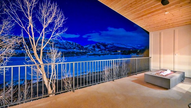 Une pièce avec vue sur un paysage enneigé, un foyer et un plafond en bois.