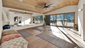 Une pièce spacieuse avec un plafond haut, un plancher en bois et de grandes fenêtres donnant sur un paysage enneigé.