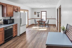 Kitchen features a dishwasher, microwave, and refrigerator, with a dining area and wooden table.