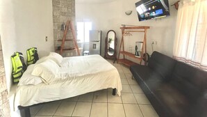 A bedroom with a bed, a black sofa, a television mounted on the wall, and a ceiling fan. - BUNGALOW POOL AND SEMI-PRIVATE BEACH, ZIPOLITE-MAZUNTE BEACH, 8 NEARBY BEACHES (San Pedro Pochutla)