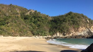 A sandy beach with clear blue water and rocky cliffs in the background. - BUNGALOW POOL AND SEMI-PRIVATE BEACH, ZIPOLITE-MAZUNTE BEACH, 8 NEARBY BEACHES (San Pedro Pochutla)