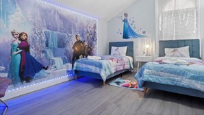 A bedroom with two beds, a large wall mural, and LED strip lighting.