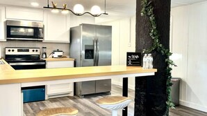 Una cucina moderna con mobili bianchi, elettrodomestici in acciaio inossidabile e un'isola centrale con sgabelli.