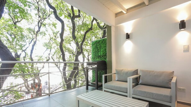 Un balcon moderne avec un canapé blanc, une table blanche et un jardin vertical vert.