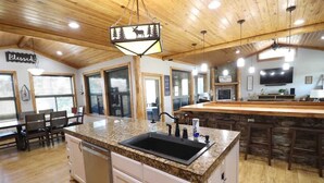 A kitchen with granite countertops, a black sink, and wooden cabinets. - Spacious Retreat on Caddo River, Amity (Amity)
