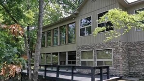 A modern building with a stone facade, large windows, and a wooden deck. - Spacious Retreat on Caddo River, Amity (Amity)
